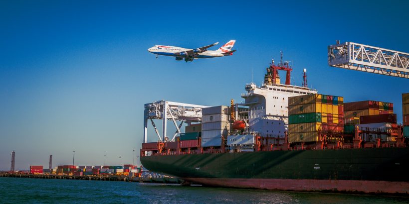 bateau avec conteneurs et avion qui passe au-dessus