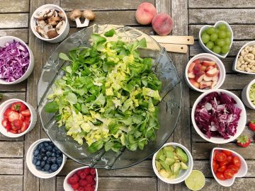 saladier de salade verte avec ingrédients pour salade composée dans des petits bols autour