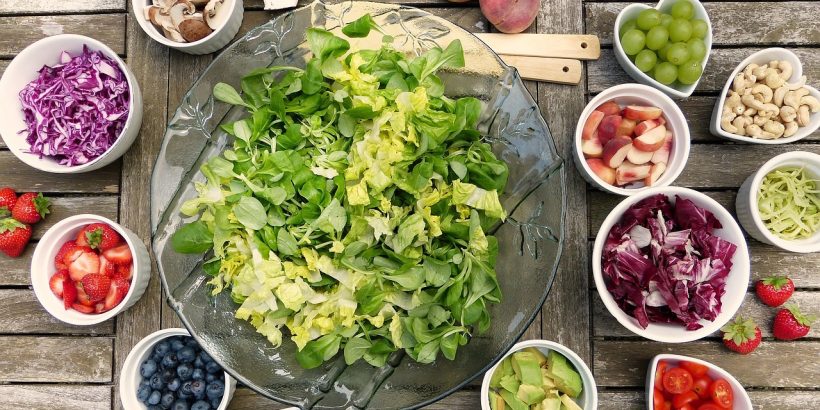 saladier de salade verte avec ingrédients pour salade composée dans des petits bols autour