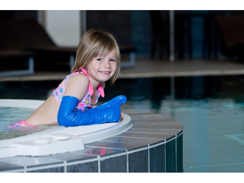 enfant avec un protège plâtre dans une piscine