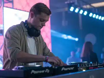 Un DJ ajustant son matériel en toute sérénité, un casque autour du cou.