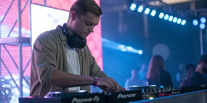 Un DJ ajustant son matériel en toute sérénité, un casque autour du cou.
